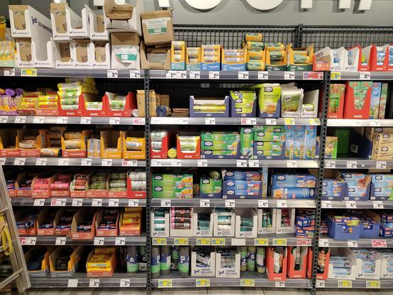 Ein Supermarktregal, dessen unterer Bereich von Mülltüten dominiert ist und während die oberen Regalböden Gefrierbeutel und andere Haushaltsfolien darbieten. 